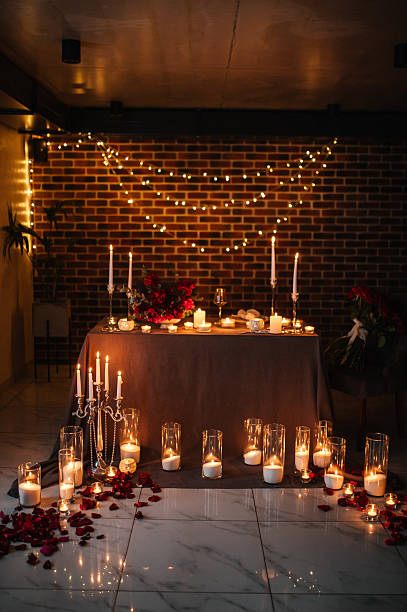 istock Candlelight date in restaurant. Romantic dinner setup at night. Champagne glasses, bouquet flowers. Table setting for couple, Valentine's Day evening, burning candles for surprise marriage proposal. 2253586533