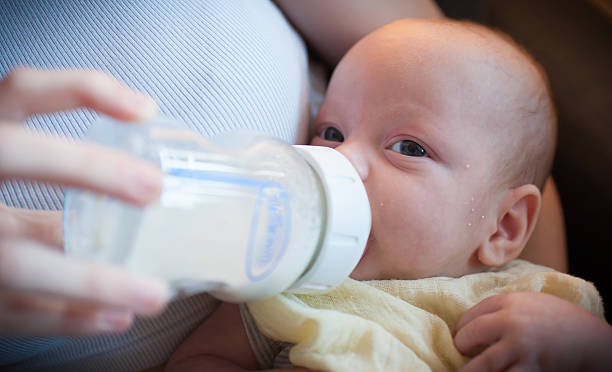 istock Baby drinks from bottle while resting in parent's lap during afternoon 2253586720