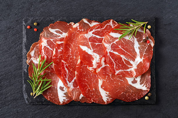 istock Sliced capicola coppa meat on dark slate board with rosemary 2253590925