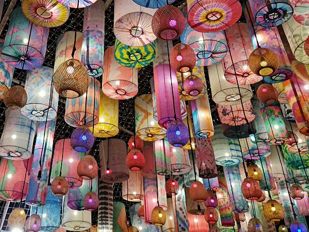Rows of colorful hanging lanterns displayed in a festive outdoor setting, creating a bright decorative pattern with vibrant colors and soft glowing light.