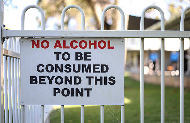 istock Warning sign. No alcohol to be consumed beyond this point. Event, demarcated area. Intoxication and public nuisance. White metal picket fence 2253592071