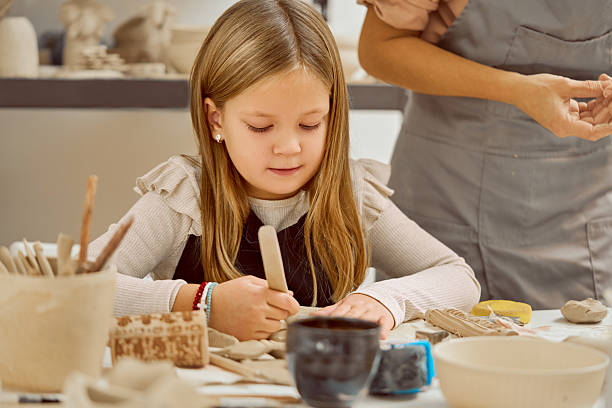 istock Young Girl Focused While Crafting Clay In Bright Pottery Studio With Instructor During Class Today 2253592487