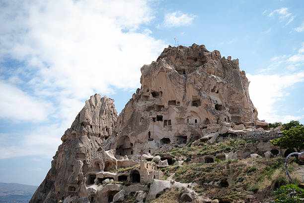 Uchisar castle, a prominent landmark in cappadocia, turkey, displaying ancient cave dwellings carved directly into the distinctive volcanic rock formations under a bright summer sky