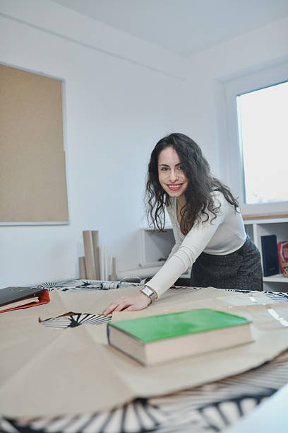 istock Atelier Scene With Designer Laying Out Completed Plans And Materials 2253603112