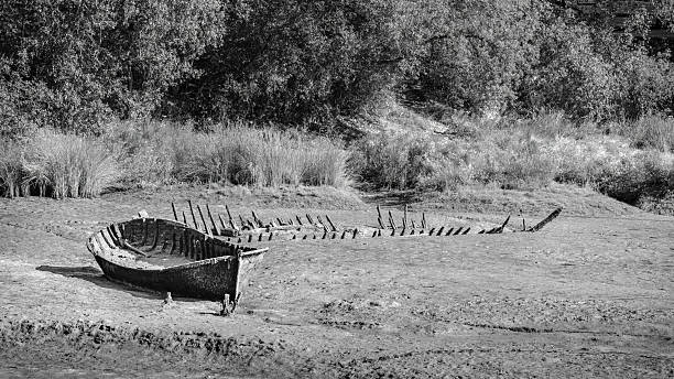 Two abandoned and wrecked boats at the bank of Ria de Barro, black and white, monochrome, 16:9