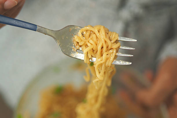 A person holds a fork with noodles, ready to enjoy a tasty dish.
