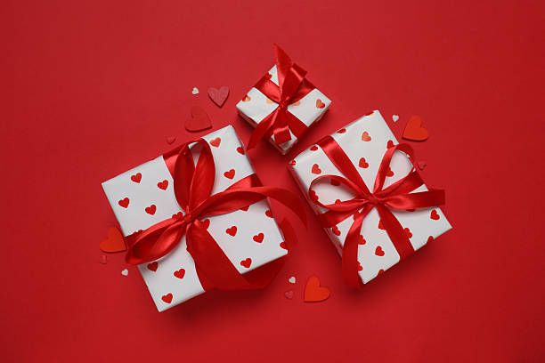 istock Festive gift boxes with red hearts on color background 2253614483