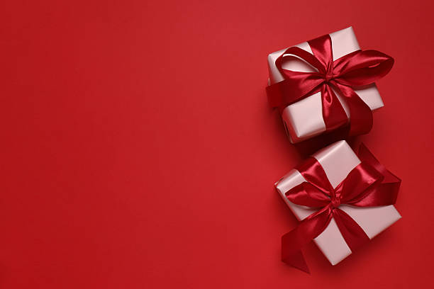 istock Festive gift boxes with red bows on color background 2253614496