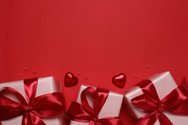istock Festive gift boxes with red hearts on color background 2253614499