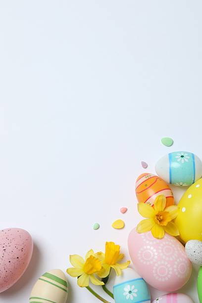 istock Happy Easter. Colorful eggs and yellow flowers on white background, space for text or advertising 2253614621