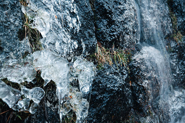 Close-up of ice formation and running water on mountain rock surface