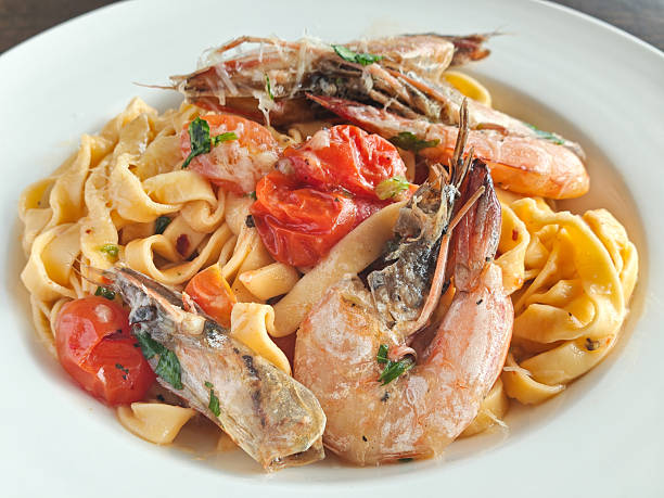 A freshly prepared plate of fettuccine with prawns in thick creamy tomato sauce.