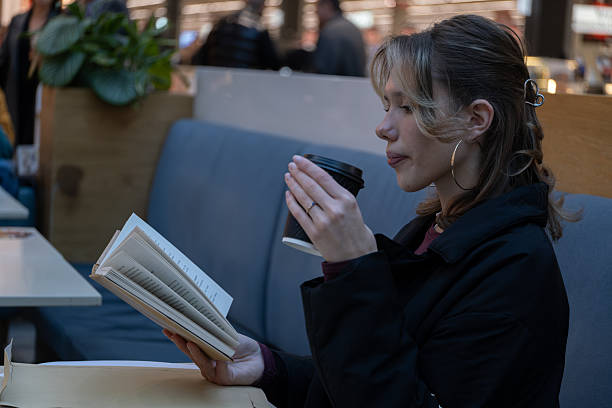 istock Woman sipping coffee while reading a book in cafe 2253630685