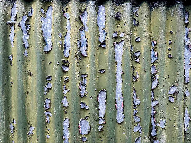 A close up of flaking paint on green corrugated metal wall on a garden shed