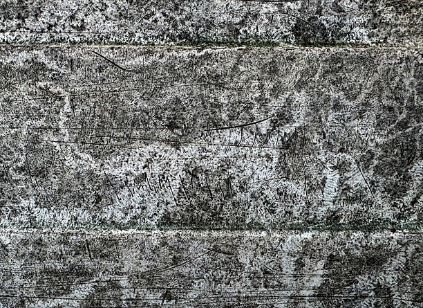 An abstract close-up of a surface with a rough, textured appearance and natural colour variations of buffs, greys, and black.