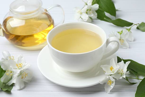 istock Green tea with jasmine in cup and teapot on light background 2253633814