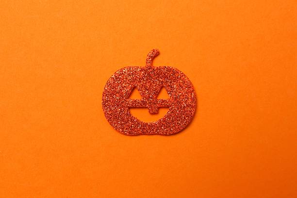 Halloween poscard with festive pumkin on orange background . Top view, space for text