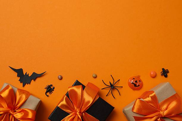 istock Halloween poscard with festive gift boxes and decorations on orange background . Top view, space for text 2253634665