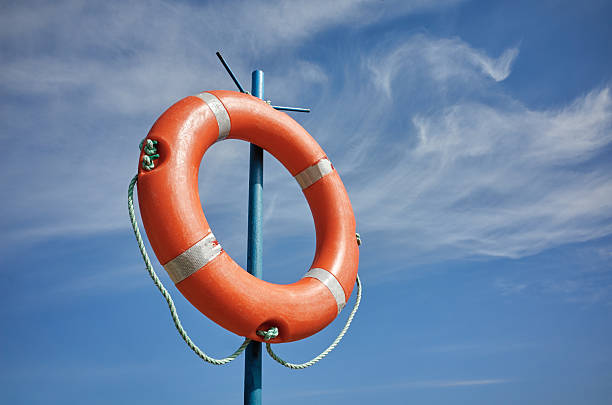 Red sunny lifebuoy on a pole white cloudy blue sky background