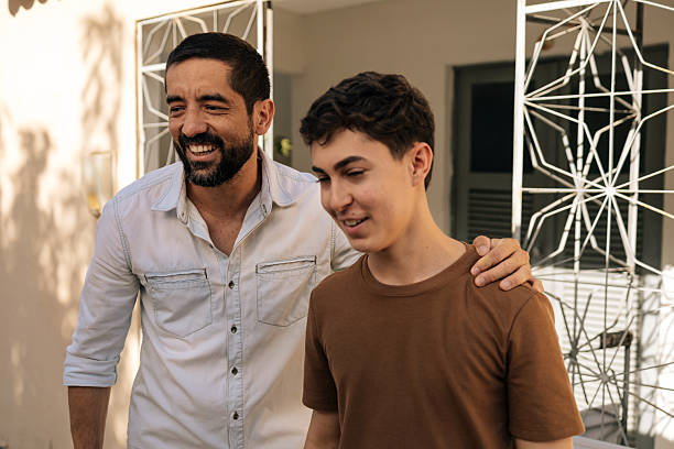 istock Father places his hand on his teenage son's shoulder while talking outdoors, expressing emotional support, trust, empathy, and a strong parent-child bond focused on wellbeing and mental health 2253640958