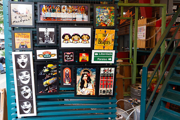 Sao Paulo, SP, Brazil - November 01 st, 2025: Humorous paintings featuring artists are for sale at the Saturday antiques fair in Benedito Calixto Square.