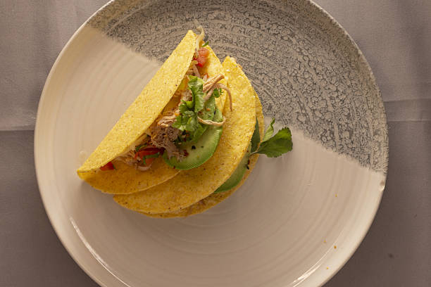 istock Handheld corn tacos with avocado and herb garnishes on plate 2253643363