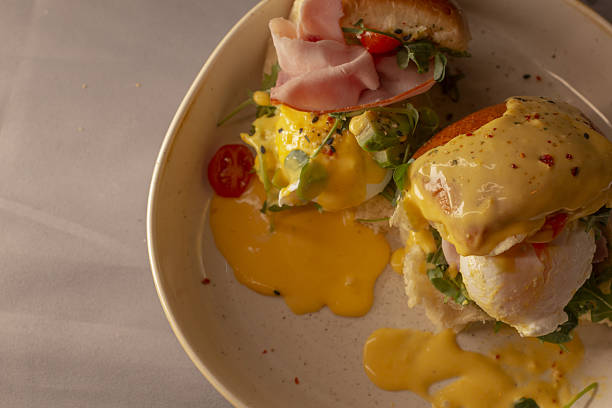 istock Warm toned editorial shot of eggs benedict with garnished ham 2253643539