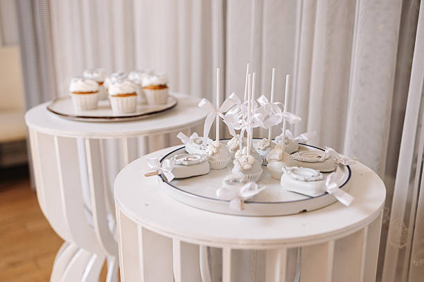 An elegant and stunning white dessert table beautifully adorned with an array of delicious cupcakes and delightful cake pops, perfect for making any celebration truly special and memorable