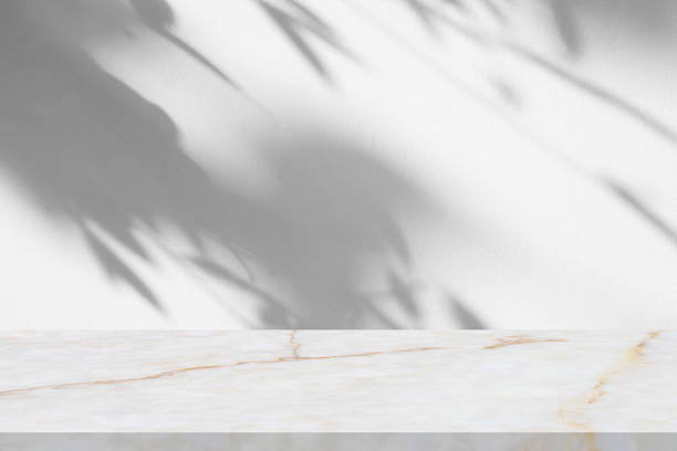 istock Marble table with tree shadow drop on white wall background for mockup product display 2253643917