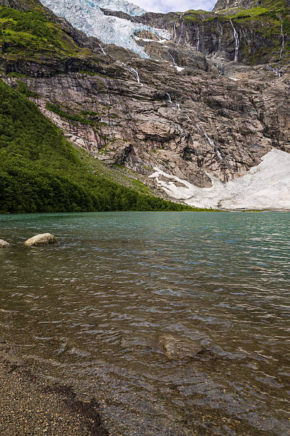 A solitary rock stands in the middle of clear water as gentle currents flow around it in a serene river during early spring.