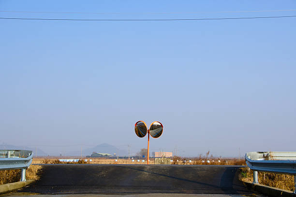 A circular reflector on an asphalt road under a blue sky