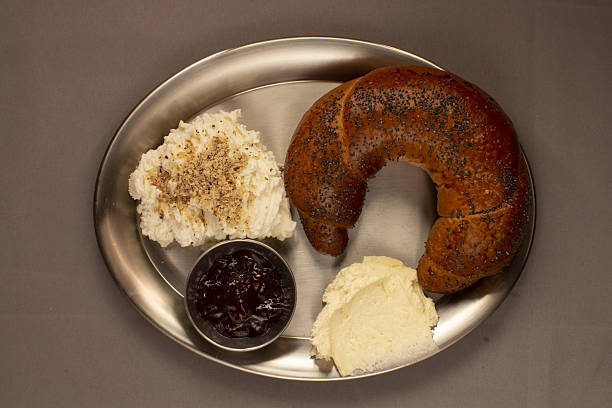 Delicious poppy seed bagel served with various spreads on breakfast tray