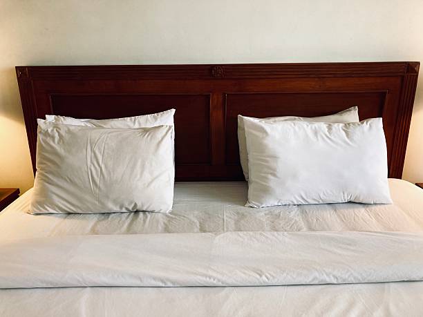 comfortable hotel bed with white pillows and dark wooden headboard