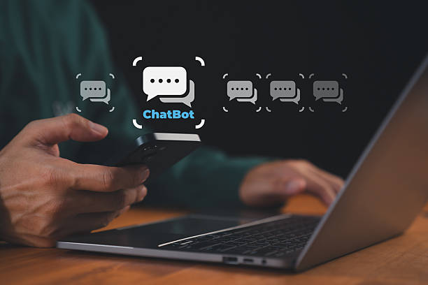 istock Person using smartphone and laptop with chatbot icons floating on screen. Concept of AI chatbot, customer support automation, assistant, online communication, messaging technology, digital service. 2253649859