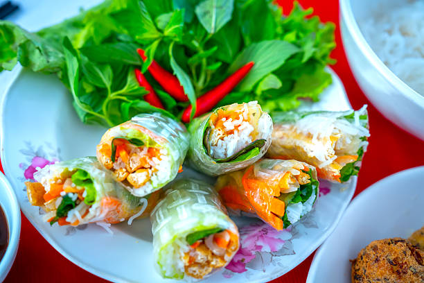 Vegetarian dish: Vegetarian spring rolls consist of vegetables rolled together, served with fresh greens and dipping sauce, skillfully arranged on the table. A favorite Vietnamese dish.