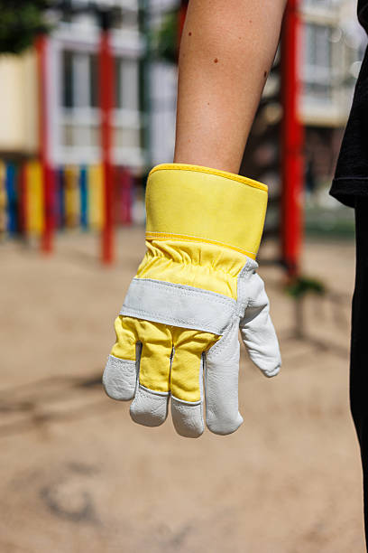 istock A bright yellow and gray work glove is being held in a hand, set against a delightful playground backdrop, an ideal combination for engaging in gardening tasks and enjoying playtime activities 2253653079
