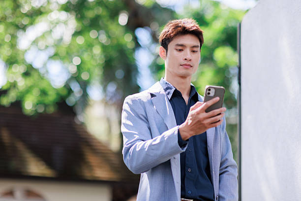 istock Young asian man using mobile phone for communication outdoors 2253655195