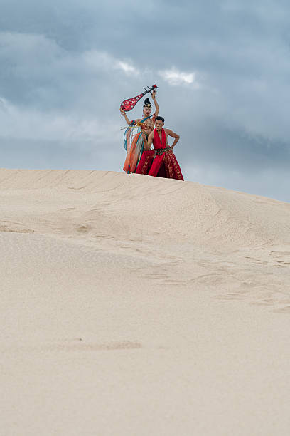 Two actors wearing period Dunhuang costumes, striking a pose on the Nam Cuong sand dunes, Ninh Thuan province, central Vietnam