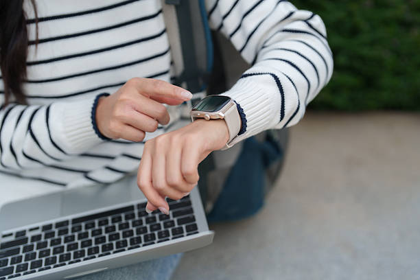 Woman checking time and notifications on her wearable device while working on laptop