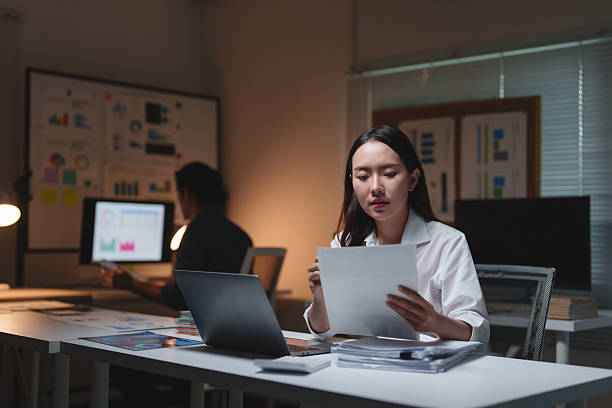 istock Young businesswoman working overtime analyzing financial documents at night 2253659069
