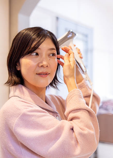 Asian woman using hair dryer in bathroom