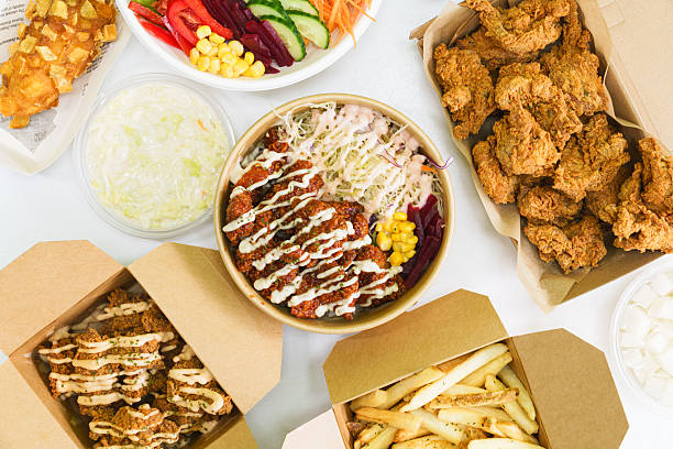 Top-down view of flat lay of assorted Asian dishes neatly arranged in takeaway boxes, ready to eat.