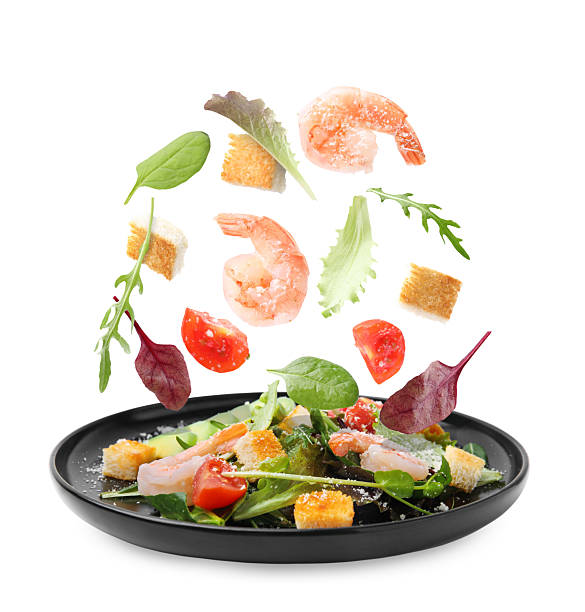 istock Ingredients falling into plate with tasty salad on white background 2253664474