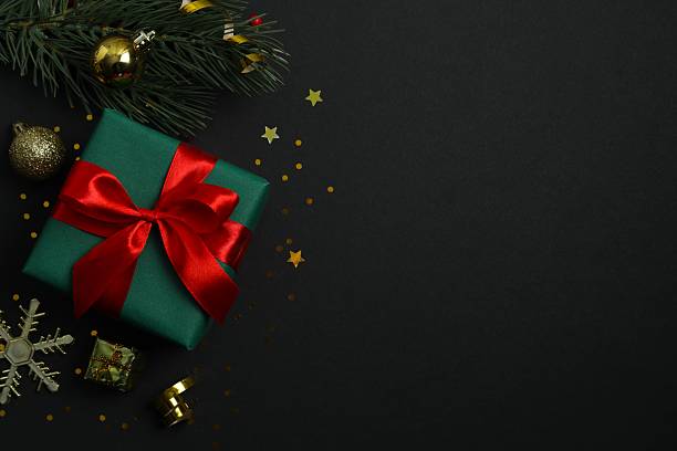 istock Beautiful gift box tied with bow and Christmas decorations on black background 2253667391