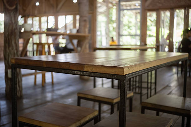 A blurred café, restaurant, or coffee shop background with a perspective view of the corner of a wooden table.
