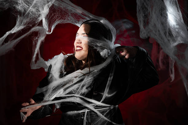 istock Concept of network. Woman in black leather coat tangled in huge white spider web on dark halloween cobwebs background 2253670821