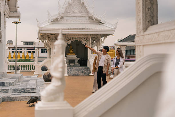 istock Young asian tourists exploring traditional thai temple architecture, learning about culture 2253670859