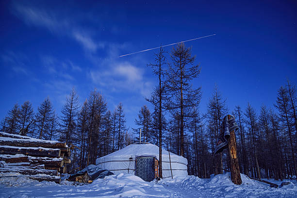 Blue hour winter scene of a traditional Tsaatan yurt surrounded by snow and larch forest, with a long-exposure light trail crossing the night sky, expressing isolation, time, and remote nomadic living. Tsagaannuur.