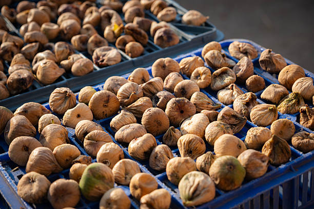 Sun dried figs drying on blue plastic crates under natural sunlight, representing a traditional agricultural process for producing healthy, organic, and sweet fruit snacks