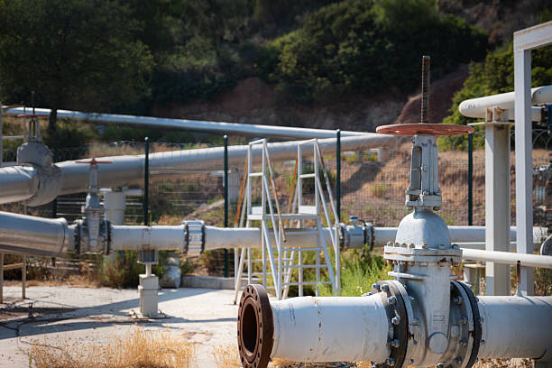 istock Industrial pipeline system showcasing complex network of metal pipes with various flanged connections, manual control valves, and structural supports in an outdoor environment under sunlight 2253690884